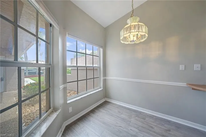 Unfurnished dining area featuring a chandelier, wood-type flooring, and vaulted ceiling