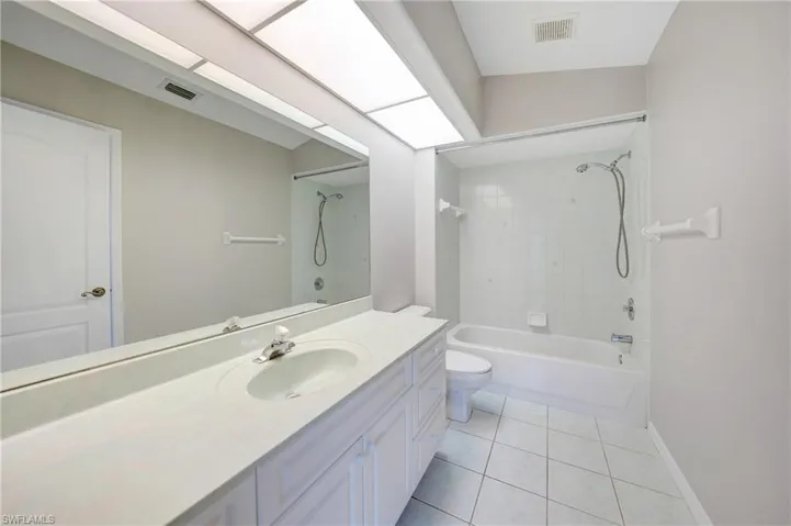 Full bathroom featuring tiled shower / bath combo, tile flooring, toilet, and large vanity