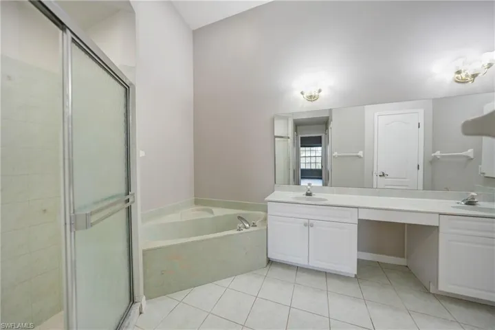 Bathroom featuring dual bowl vanity, tile flooring, and independent shower and bath