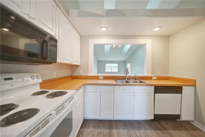Kitchen with white cabinets, dark hardwood / wood-style flooring, dishwasher, range, and sink