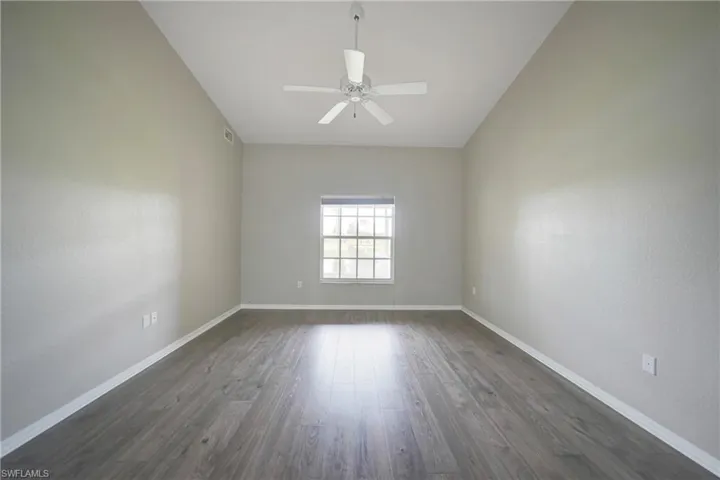 Spare room with ceiling fan, vaulted ceiling, and dark hardwood / wood-style flooring