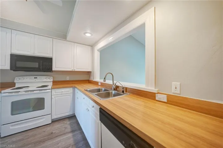 Kitchen featuring electric range, white cabinets, and dark wood-type flooring