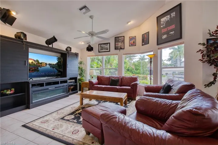 Living room featuring vaulted ceiling, ceiling fan, and tile patterned floors