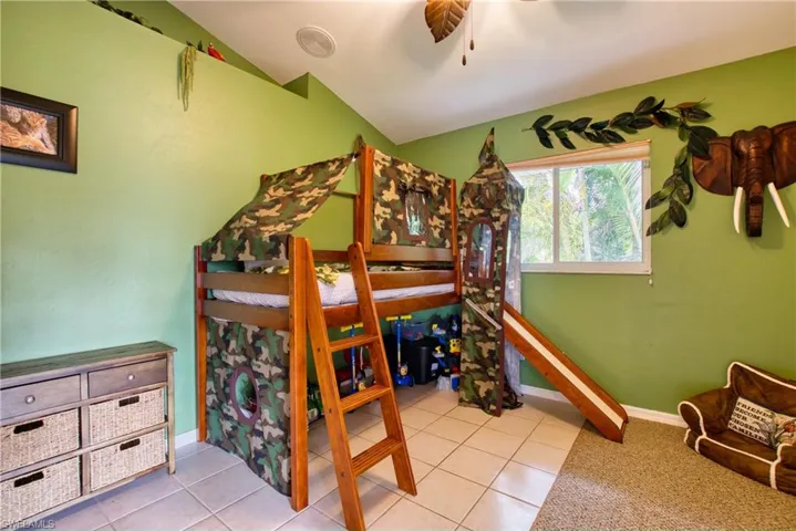 Bedroom with light tile patterned floors, ceiling fan, and lofted ceiling