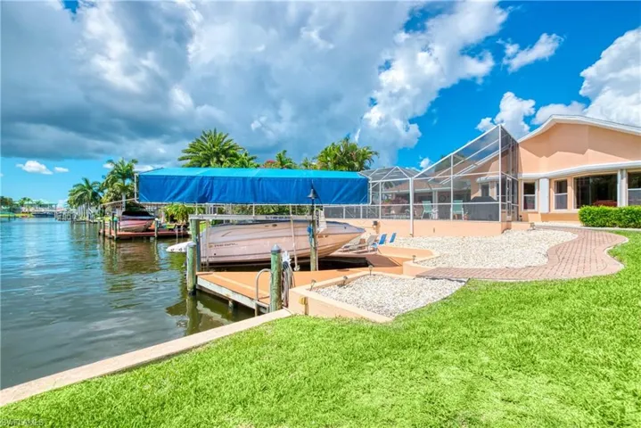 Dock with boat lift, a sunroom, glass enclosure, and a yard
