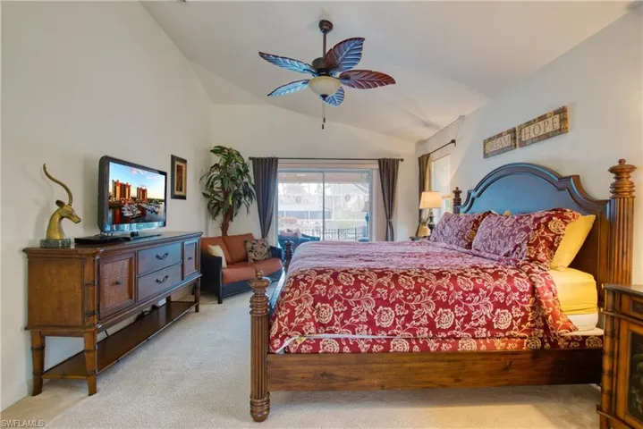Bedroom featuring vaulted ceiling, access to outside, carpet, and a ceiling fan