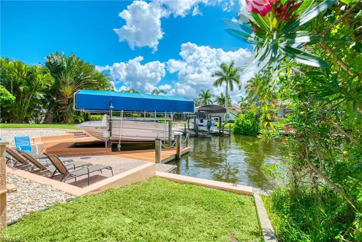 Dock area featuring boat lift, a water view, and a yard