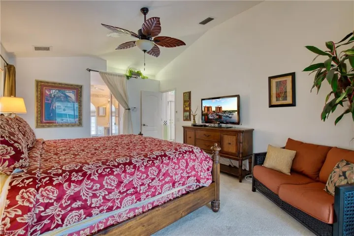 Carpeted bedroom with vaulted ceiling and a ceiling fan