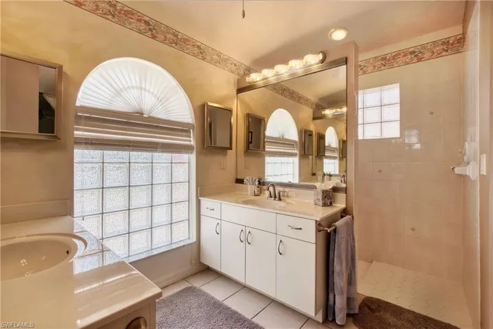Bathroom featuring two vanities, walk in shower, and light tile patterned floors