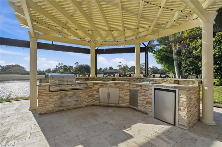 Pergola with outdoor kitchen featuring granite tops,  Bull gas grill, warming drawer, beverage refrigerator, seating for 8 (the 8 bar stools stay with the home).