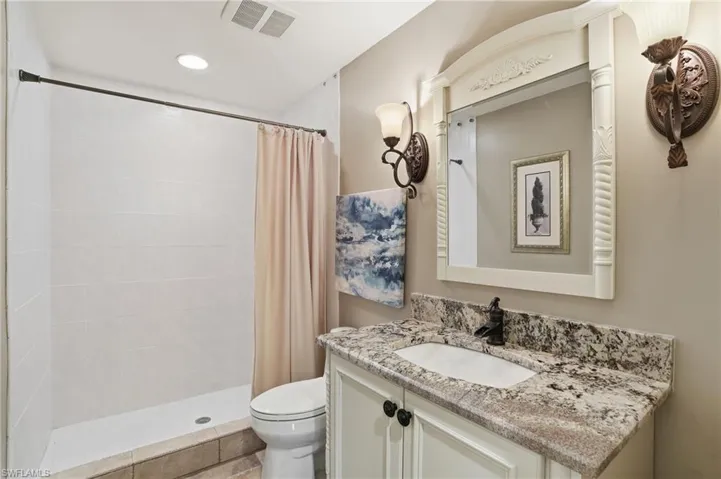 Guest bath with tiled walk-in shower, granite tops, new vanity, sconce lighting.