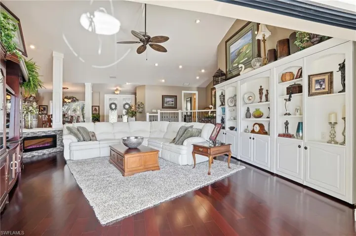 Formal living area with cherry wood floors, recessed fireplace, ceiling fan, pocketing sliders, built-in book shelves with lots of storage behind them.
