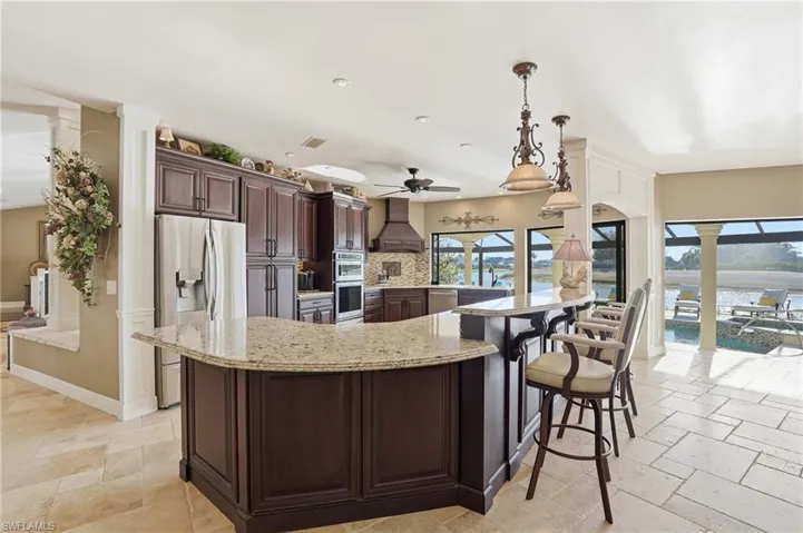 Stunning chefs kitchen with breakfast bar, stainless steel appliances, pendant lighting, Travertine floors, quartz counter tops.