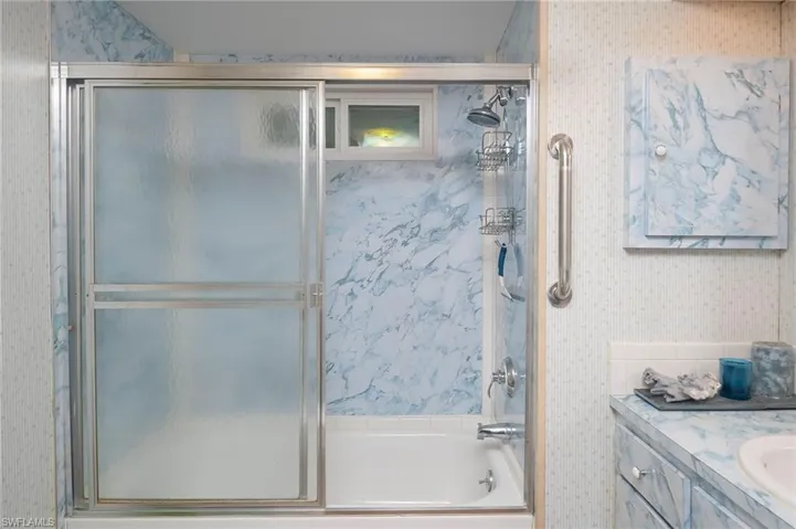 Bathroom with vanity and bath / shower combo with glass door
