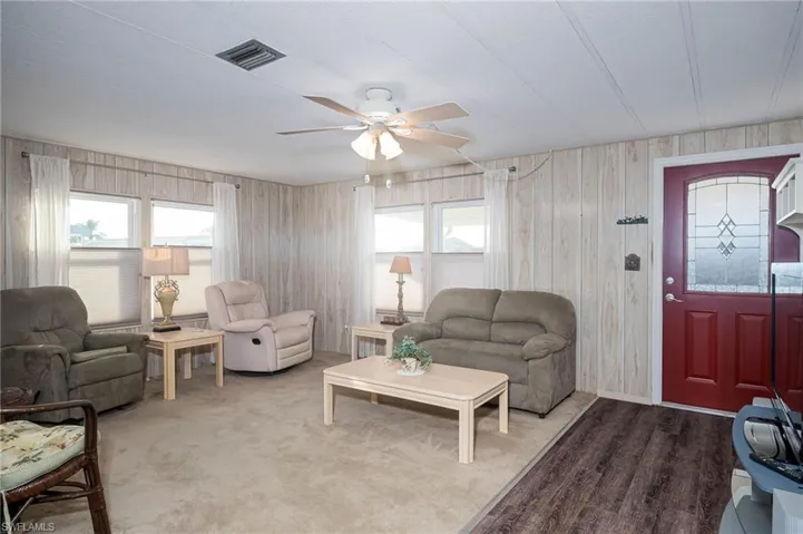 Living room with ceiling fan, wood walls, and wood-type flooring