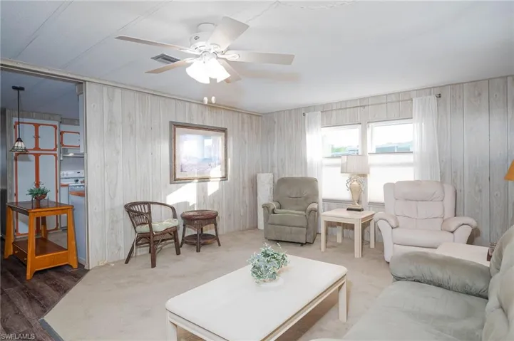 Living room featuring ceiling fan, wood walls, and wood-type flooring