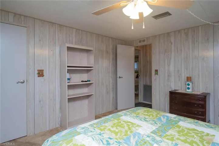 Carpeted bedroom with ceiling fan and wooden walls