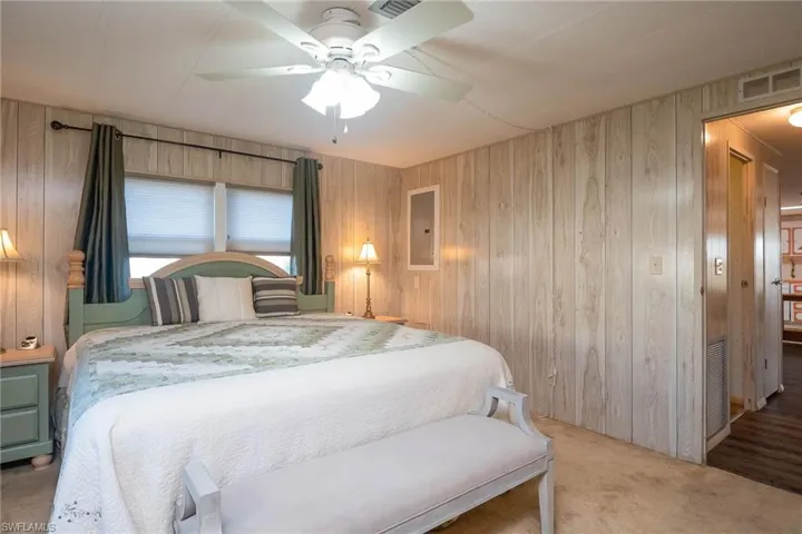 Bedroom with ceiling fan, wood walls, and carpet floors
