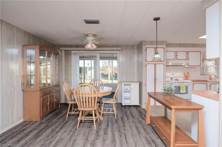 Dining room with dark hardwood / wood-style flooring, ceiling fan, and wood walls