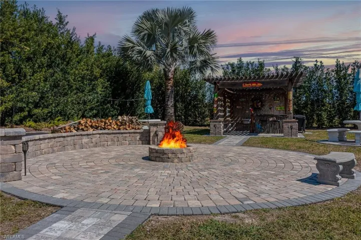 Patio terrace at dusk with a fire pit and a pergola