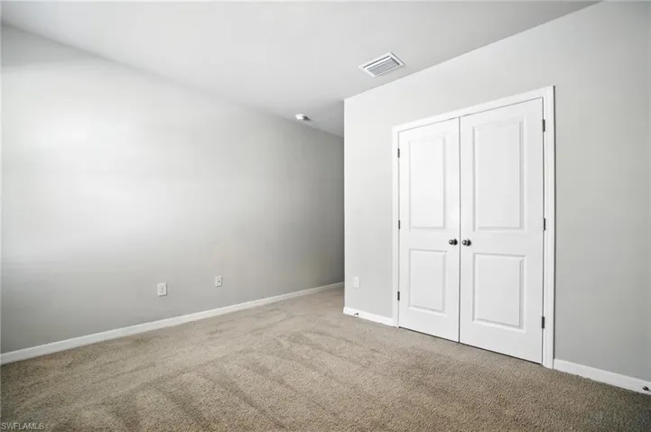 Carpeted room featuring light gray walls, white baseboards, and dual white paneled doors with dark hardware