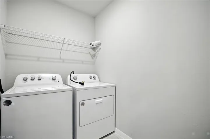 Dedicated laundry area featuring a wire storage shelf, white walls, and a light-toned flooring