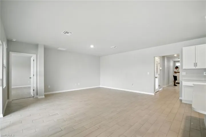 Spacious room featuring light-toned tile flooring, recessed lighting, and crisp white baseboards