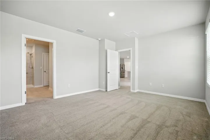 Spacious room featuring neutral carpet flooring, light gray walls, white baseboards, and overhead recessed lighting