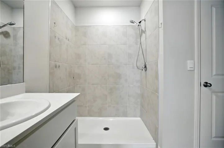 Shower enclosure with light-toned tiled walls and a white base