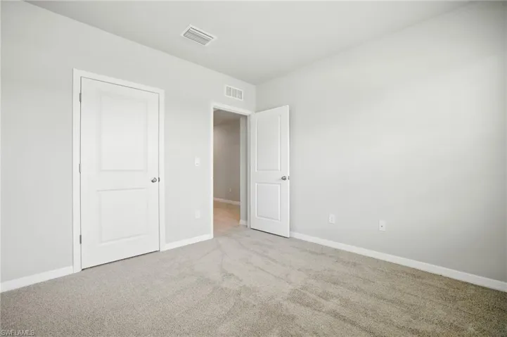 Neutral tone wall paint, light gray carpet flooring, white trim, and white two-panel interior doors