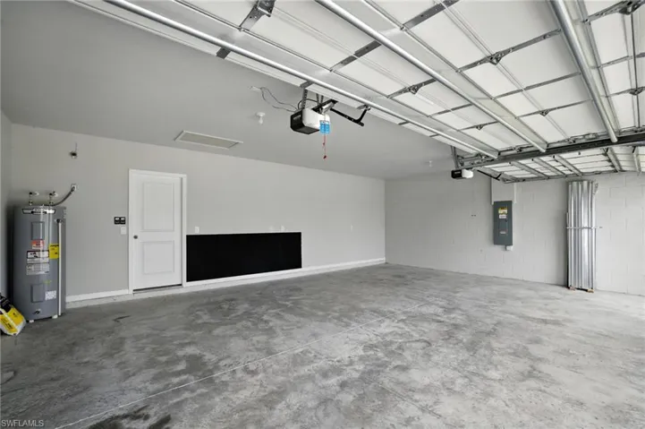 Spacious two-car garage featuring a concrete floor, light gray painted walls, a white service door, and an overhead garage door with an automatic opener