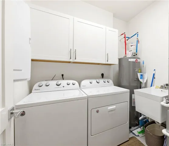 Laundry area with water heater, washer and clothes dryer, and cabinet space