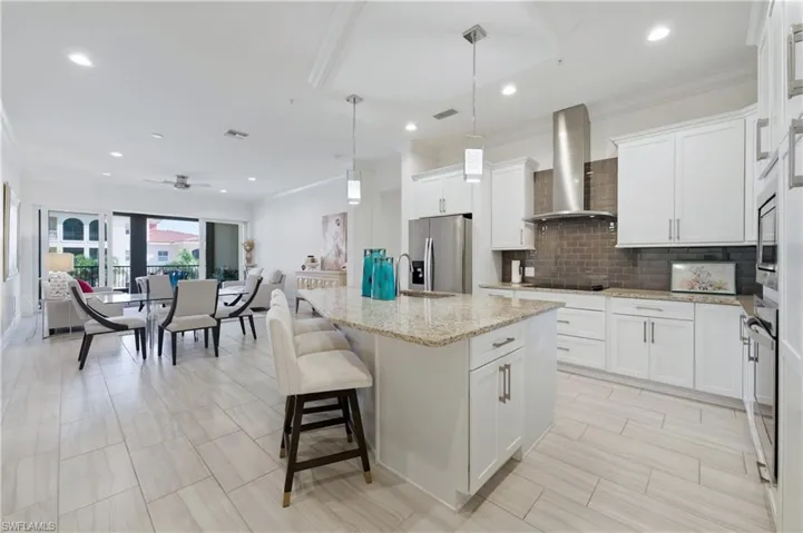 Kitchen with custom cabinets and large island with glass cooktop and recessed lighting