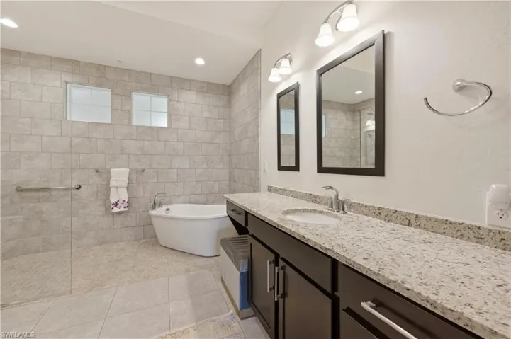 Bathroom with vanity, walk in shower, a soaking tub, light tile patterned flooring, and recessed lighting