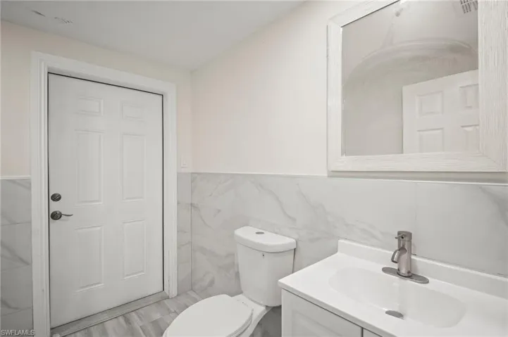 Bathroom with tile walls, vanity, and a wainscoted wall