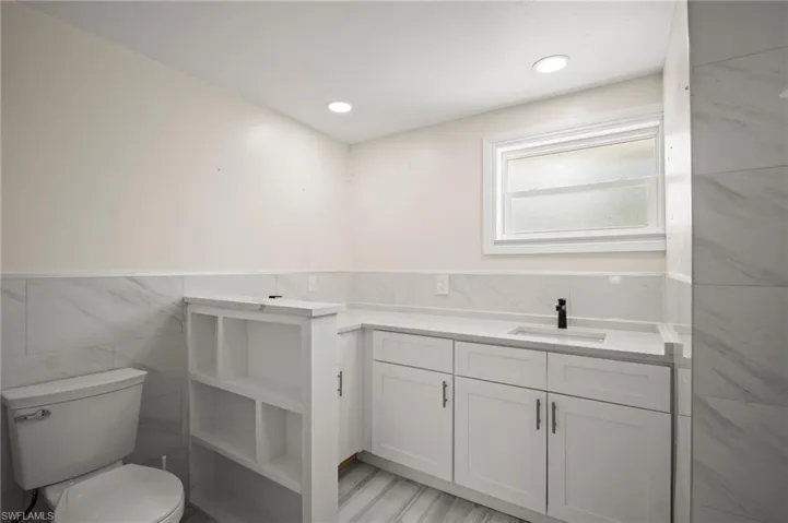 Bathroom featuring tile walls, vanity, and a wainscoted wall