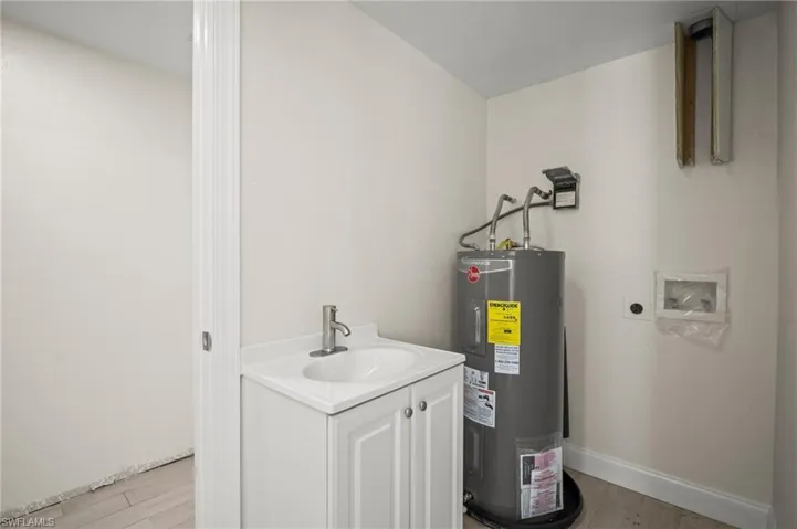 Utility room featuring electric water heater and a sink