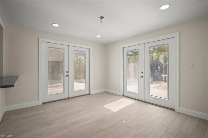 Doorway with french doors, light wood-style flooring, and recessed lighting