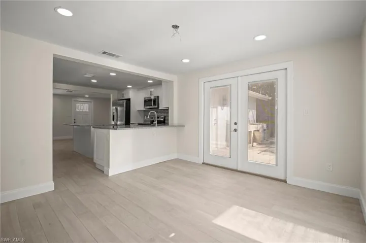Kitchen featuring french doors, stainless steel appliances, white cabinets, a peninsula, and light wood finished floors