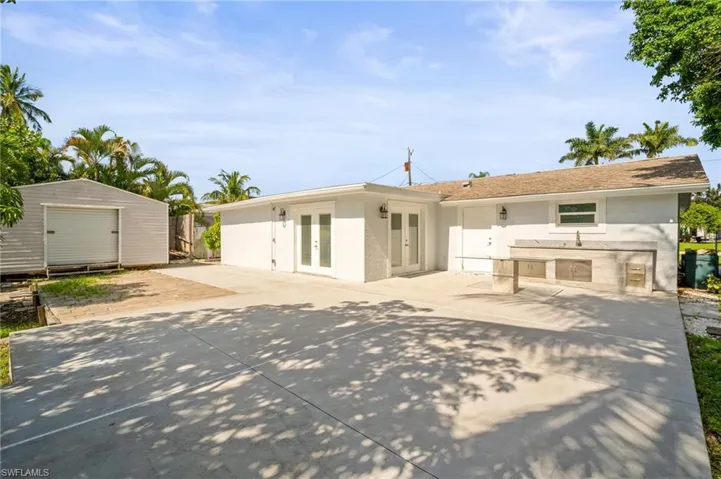 Back of house featuring french doors, a patio, an outdoor kitchen, and an outdoor structure