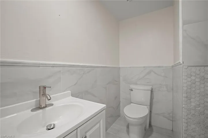 Bathroom featuring wainscoting, vanity, and tile walls