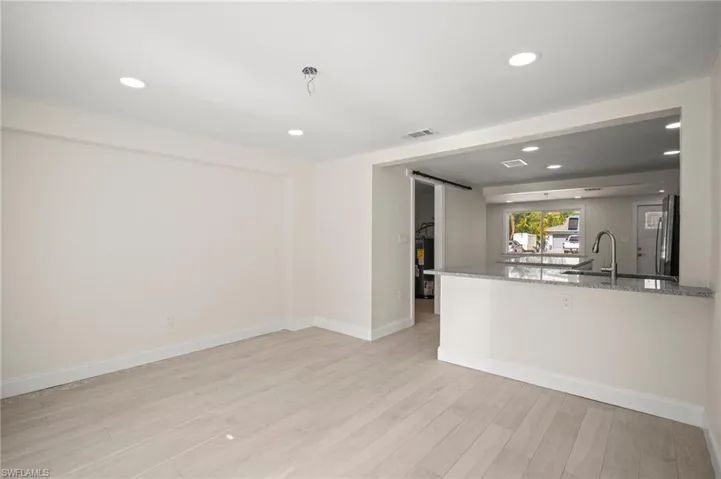 Unfurnished living room with light wood-style floors, recessed lighting, and a barn door