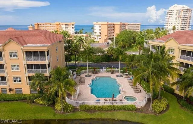 Community pool featuring a community hot tub, a water view, and a patio