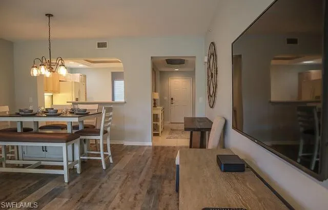 Dining room featuring dark wood-style flooring, suspended lighting, and arched walkways