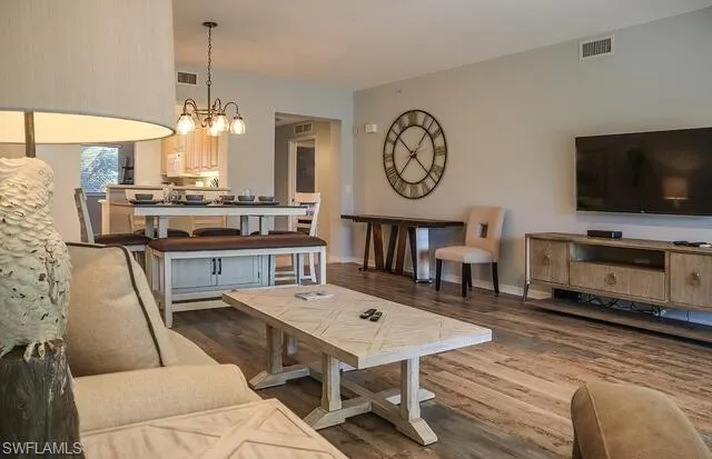 Living room with dark wood-type flooring and a chandelier