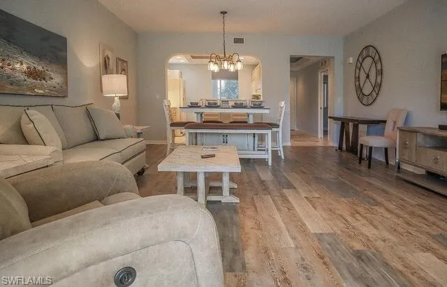 Living area with suspended lighting, wood finished floors, and arched walkways