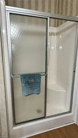 Full bath featuring a shower stall and wood finished floors