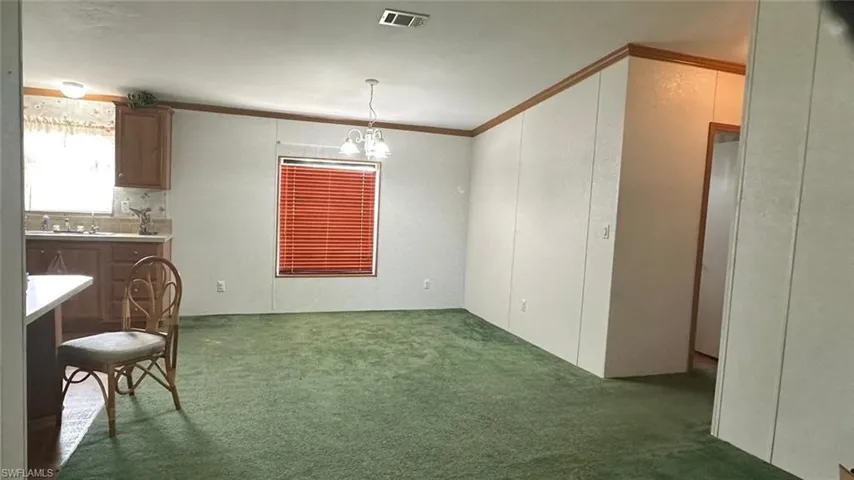 Unfurnished dining area with ornamental molding, carpet flooring, and a chandelier