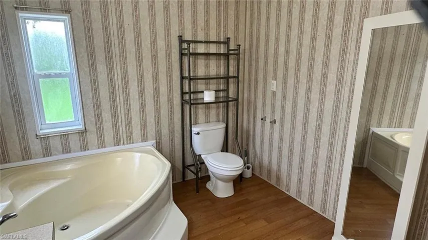Full bathroom with wood finished floors, a bath, and healthy amount of natural light