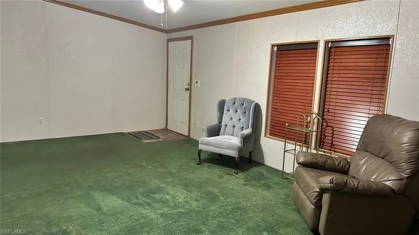 Living area featuring carpet flooring, crown molding, and a ceiling fan